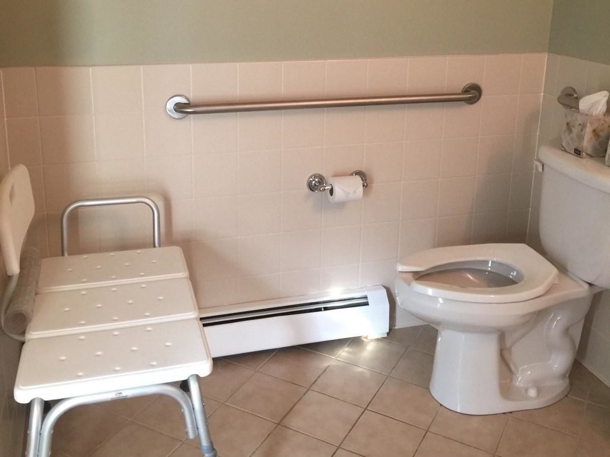 Ein Badezimmer mit erhöhter Toilette, Haltegriff und Handtuchwärmer.