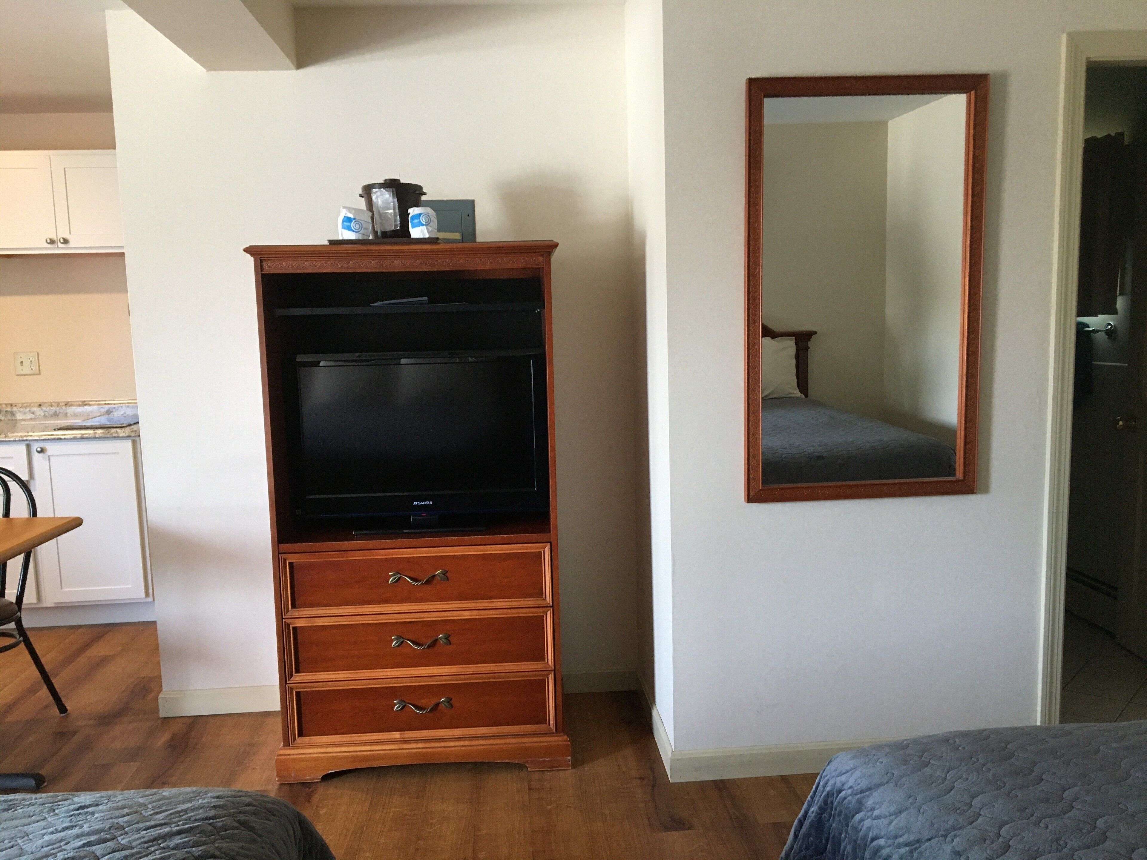 A room with a wooden entertainment center, a mirror, and a bed.