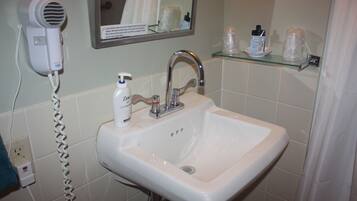 A bathroom with a white sink, a hairdryer, and a mirror.