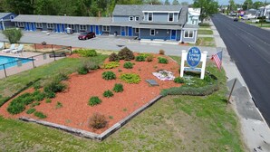 A motel with a landscaped garden, a swimming pool, and a sign indicating the motel name. - The Towne Motel (Skowhegan)