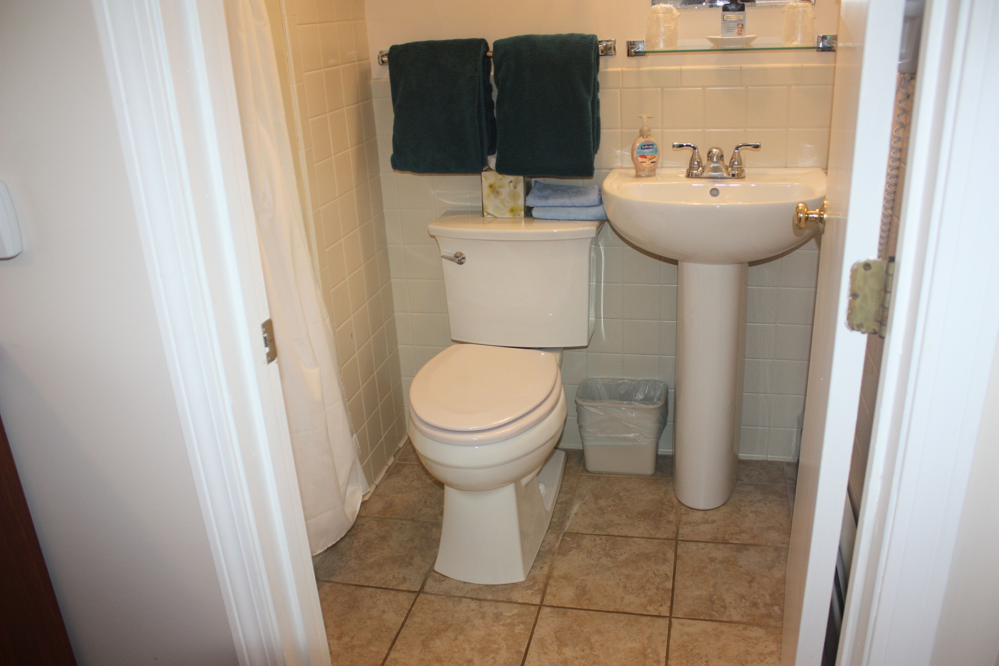 A bathroom with a toilet, sink, and two towels hanging on the wall.