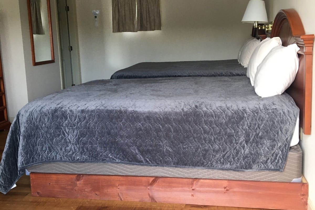 A bedroom with a large bed, wooden headboard, and a bedside lamp.