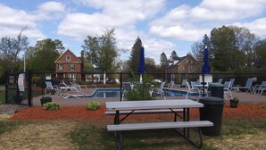 A fenced outdoor area with a pool, lounge chairs, and a picnic table. - The Towne Motel (Skowhegan)