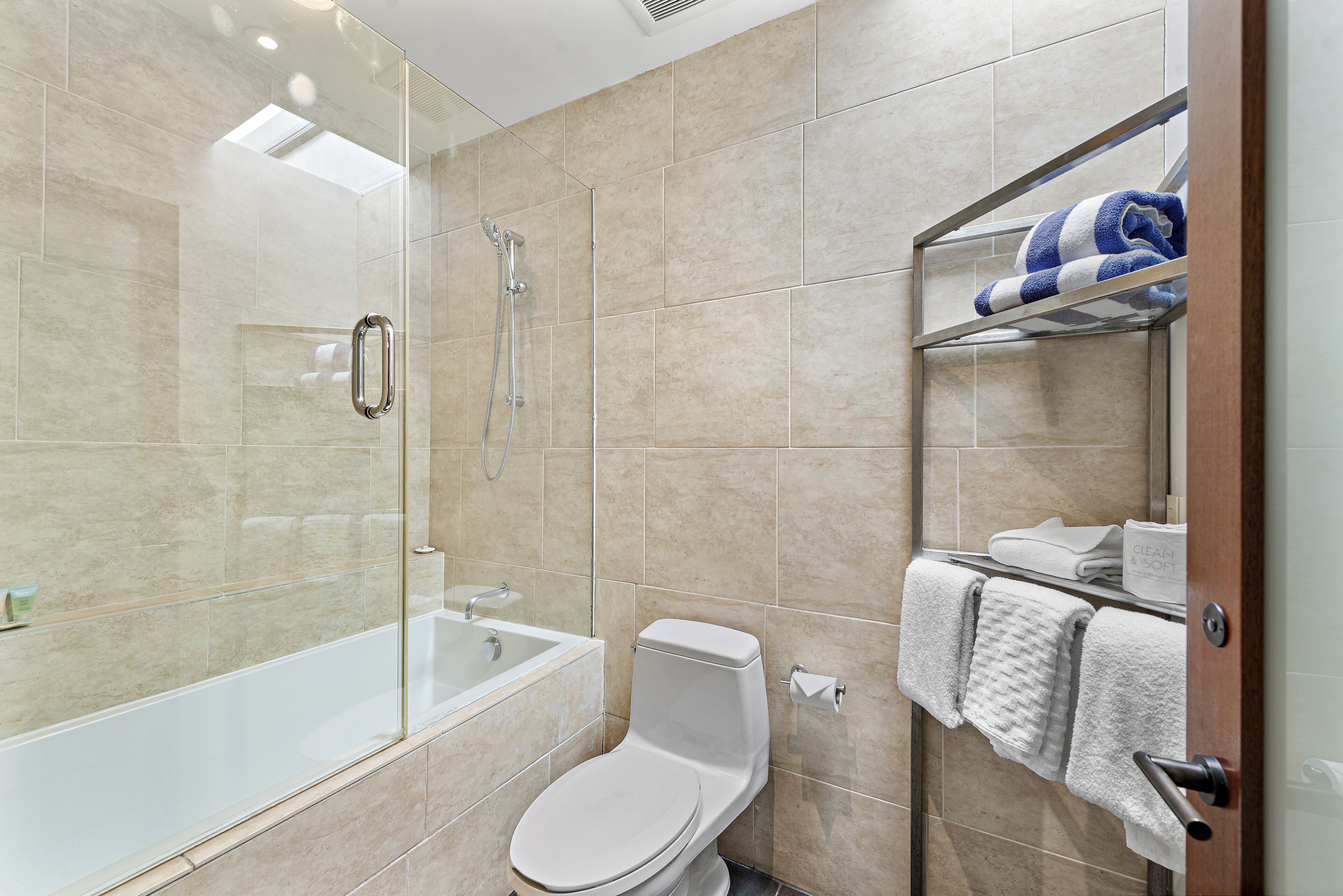 A modern bathroom with a glass-enclosed shower, a bathtub, and a toilet.