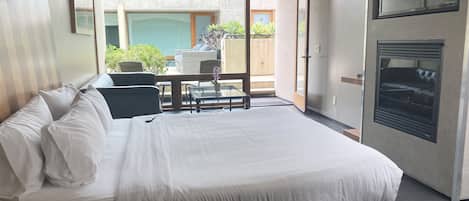 Une chambre moderne avec un grand lit, une table en verre et une vue sur la terrasse extérieure.