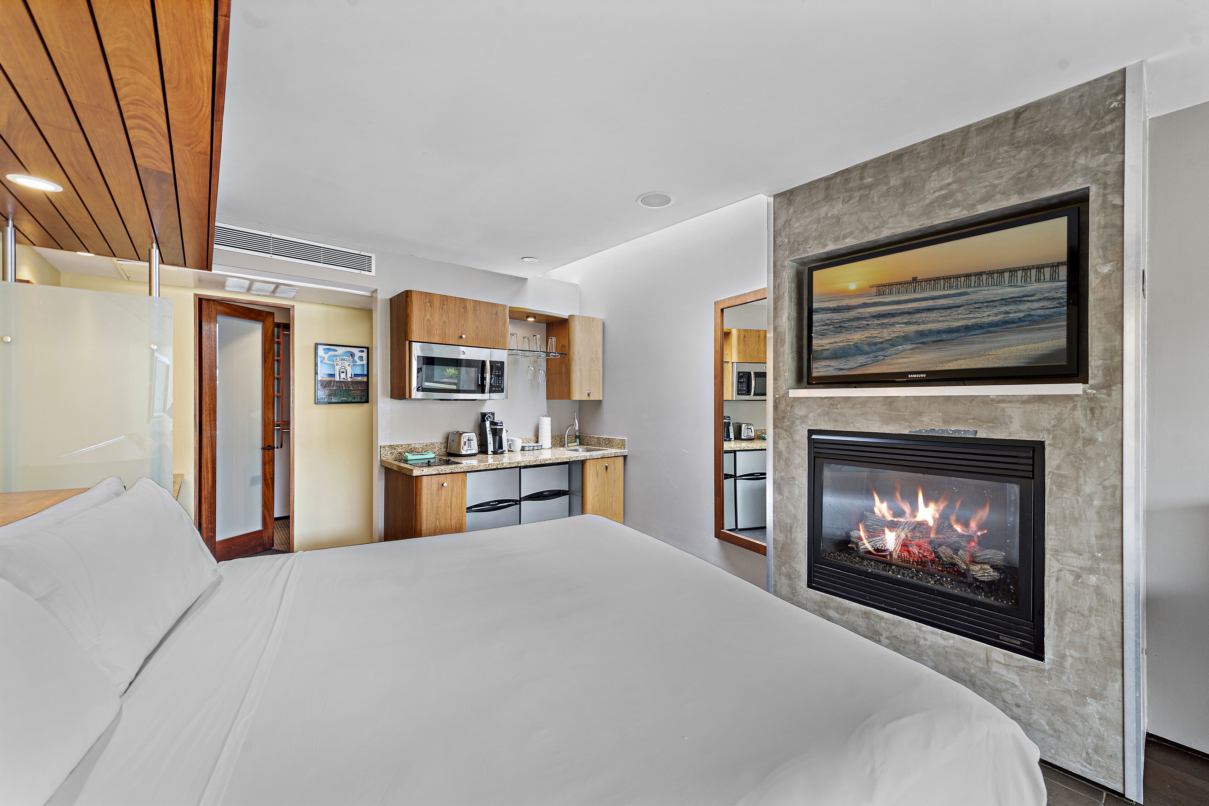 Una habitación de hotel moderna con cama, kitchenette y chimenea.