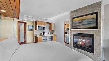 Una habitación de hotel moderna con cama, kitchenette y chimenea.