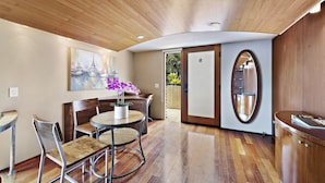 A modern interior with a wooden ceiling, a round dining table with chairs, a potted plant, and a large mirror. - 14 West Hotel (Laguna Beach)