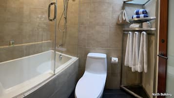 Un baño moderno con ducha envuelta en vidrio, inodoro blanco y toallero con toallas ordenadas.