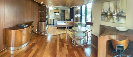 A modern kitchen with wooden cabinetry, a dining area with a round table and chairs, and a large window providing a view of the outside.