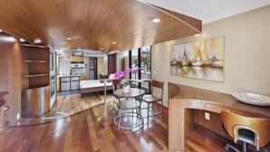 Une cuisine moderne avec un plancher en bois, un coin repas avec une table ronde et des chaises, et un grand tableau accroché au mur.