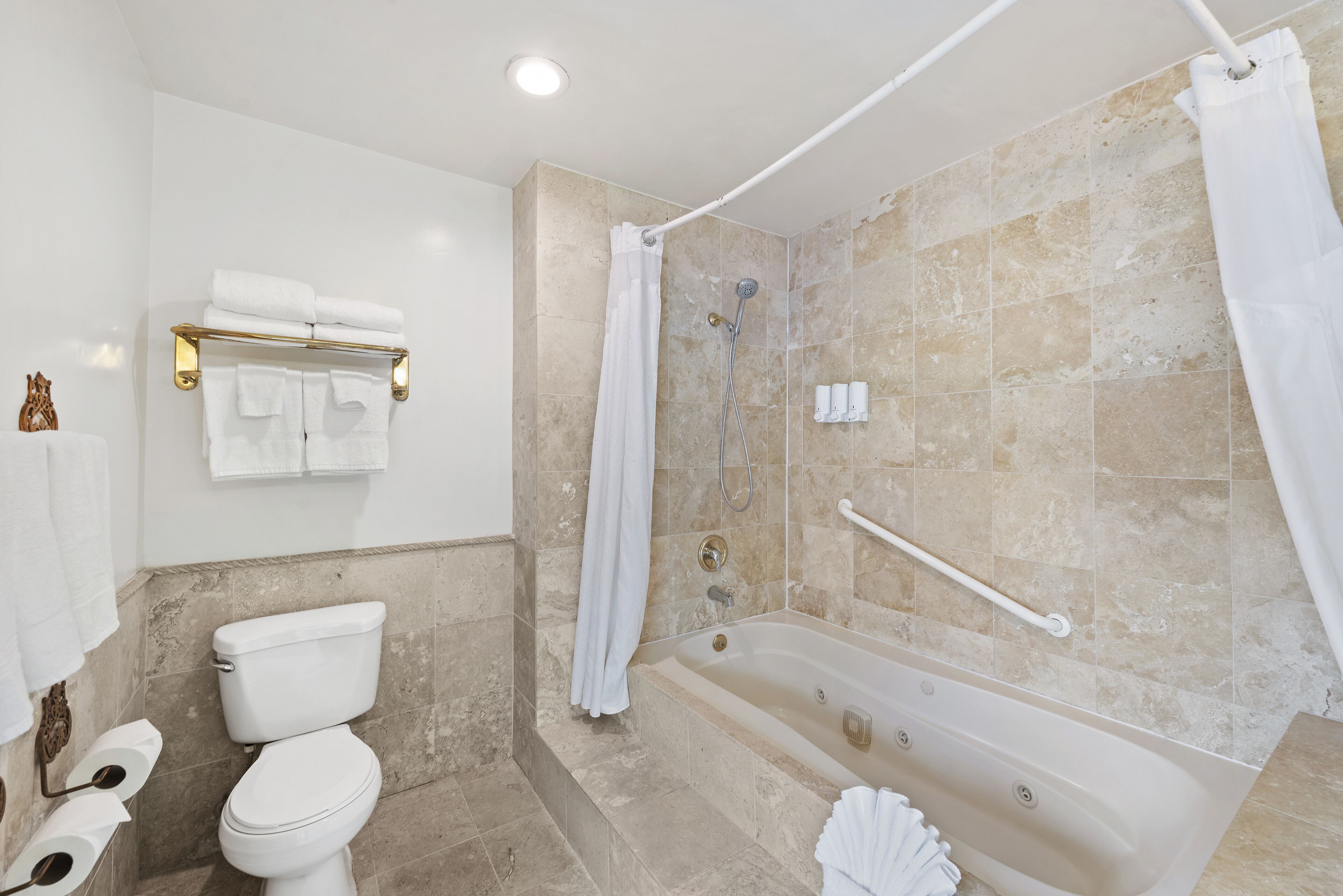 A bathroom with a toilet, bathtub, shower, and towel rack.