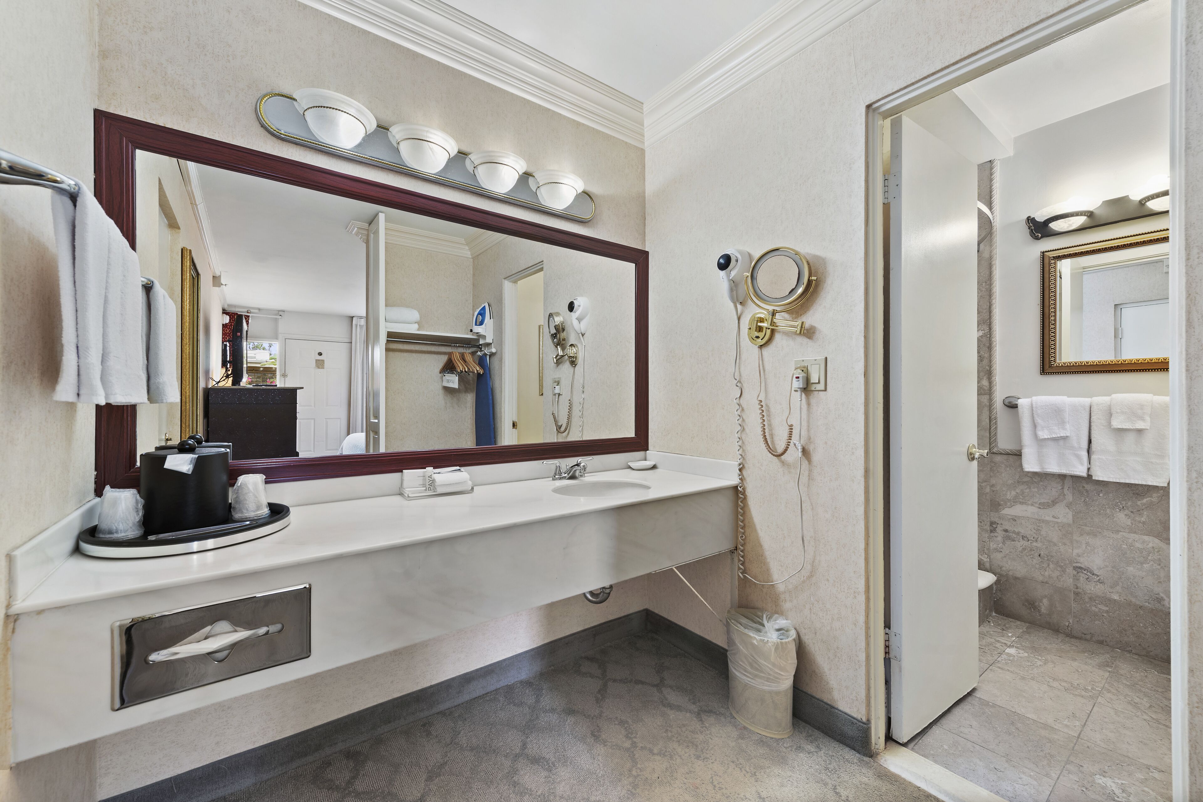Un baño moderno con un espejo grande, un lavamanos y una zona de ducha.