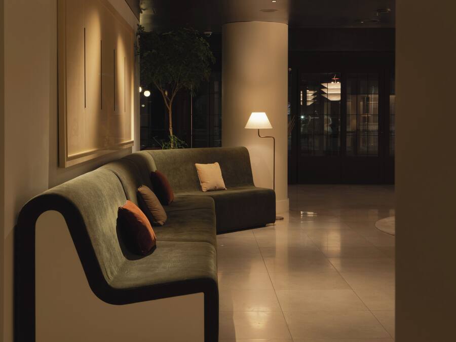 A modern lobby with a sofa, a floor lamp, and a large column.