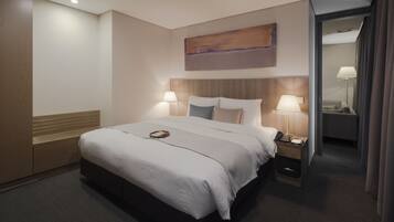 Habitación de hotel con una cama grande, lámparas de noche, cabecero de madera, un cuadro en la pared y una mesita de noche con un teléfono.