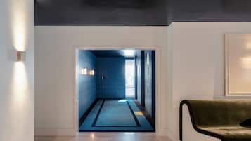 A hallway with a blue-tiled wall, a dark ceiling, and a light-colored floor.
