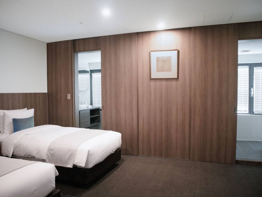 A hotel room with a large bed, a wardrobe, a mirror, and a door leading to a balcony.