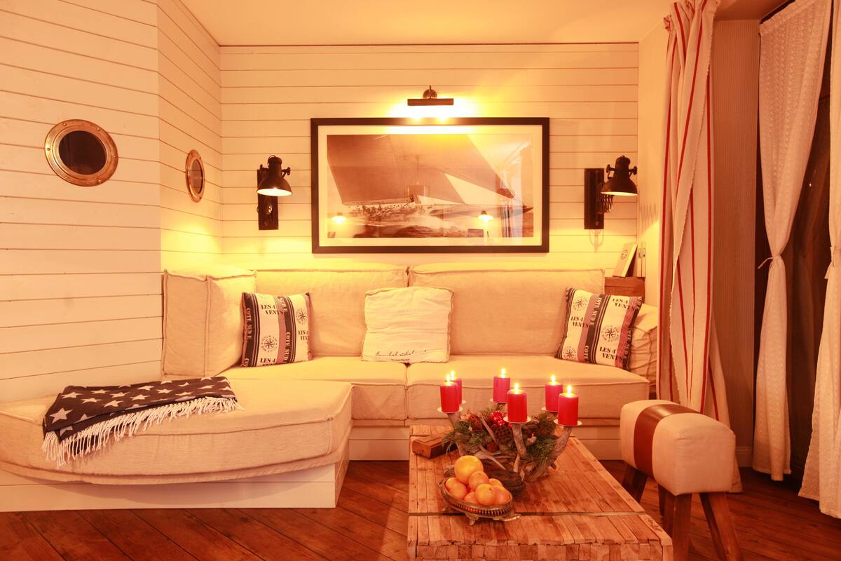 A cozy living room with a sofa, a coffee table with fruit, and candles.