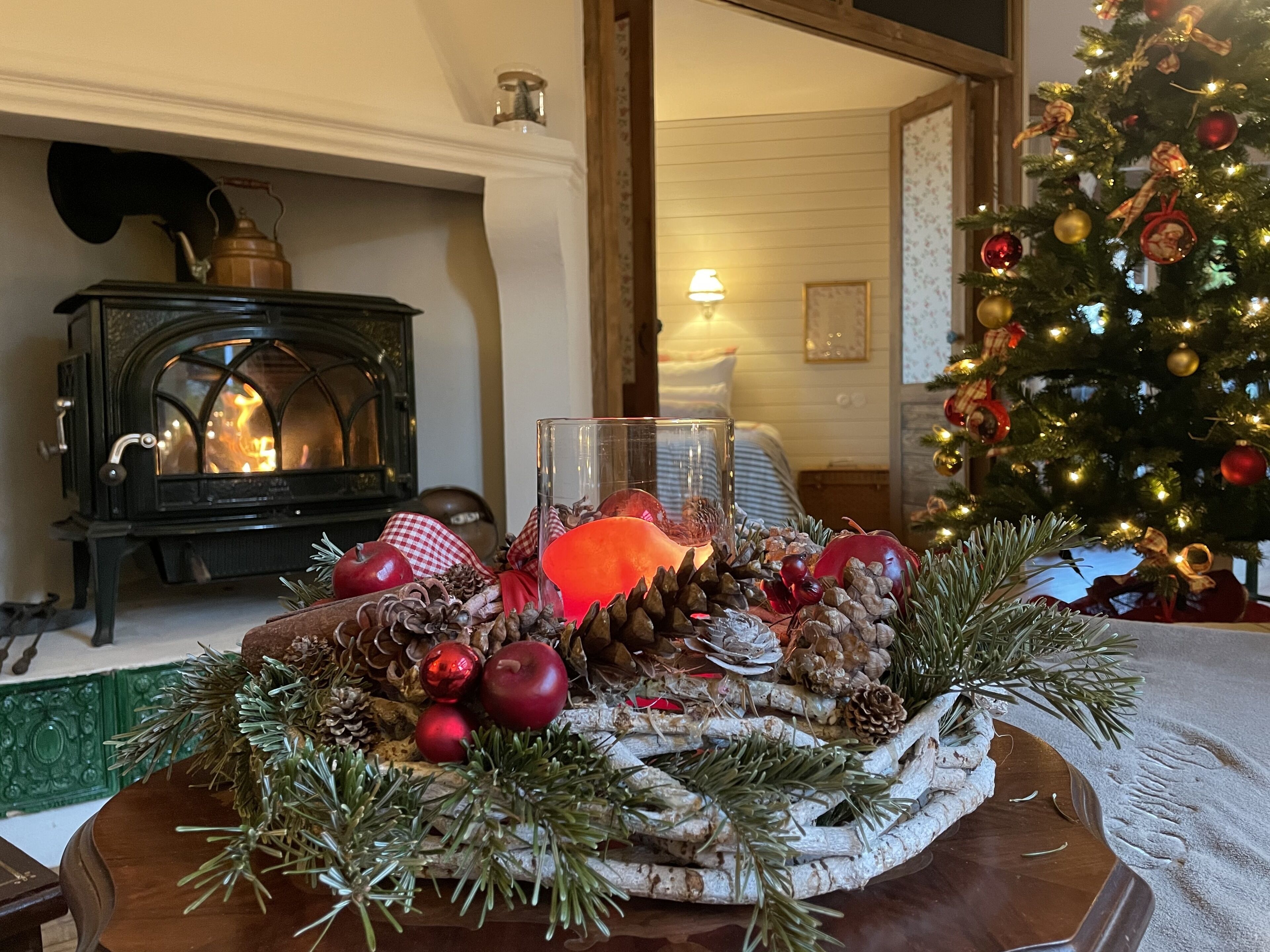 A cozy living room with a fireplace, a Christmas tree, and a decorative centerpiece on the table.