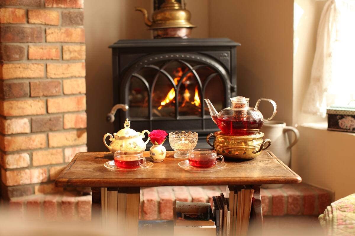 A cozy room with a brick fireplace, a table with tea sets, and books.