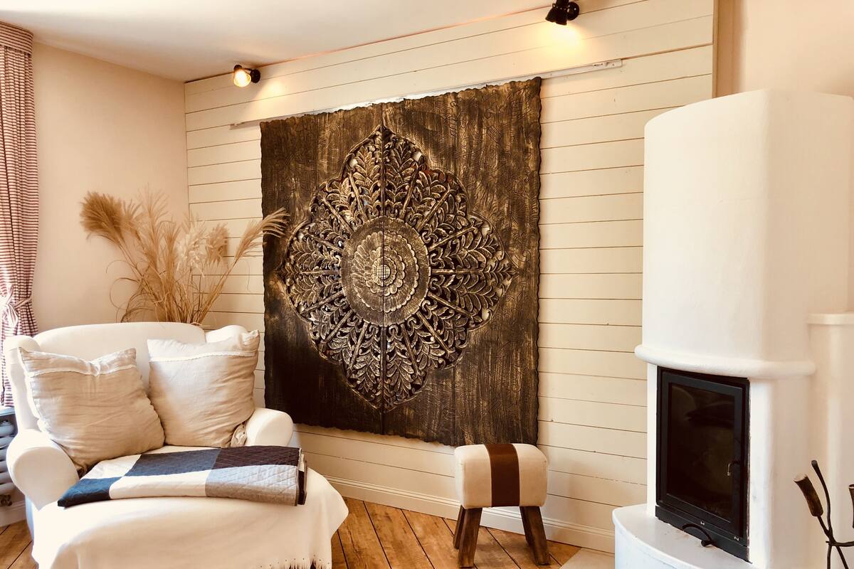 A cozy living room with a white sofa, a decorative wall hanging, and a fireplace.