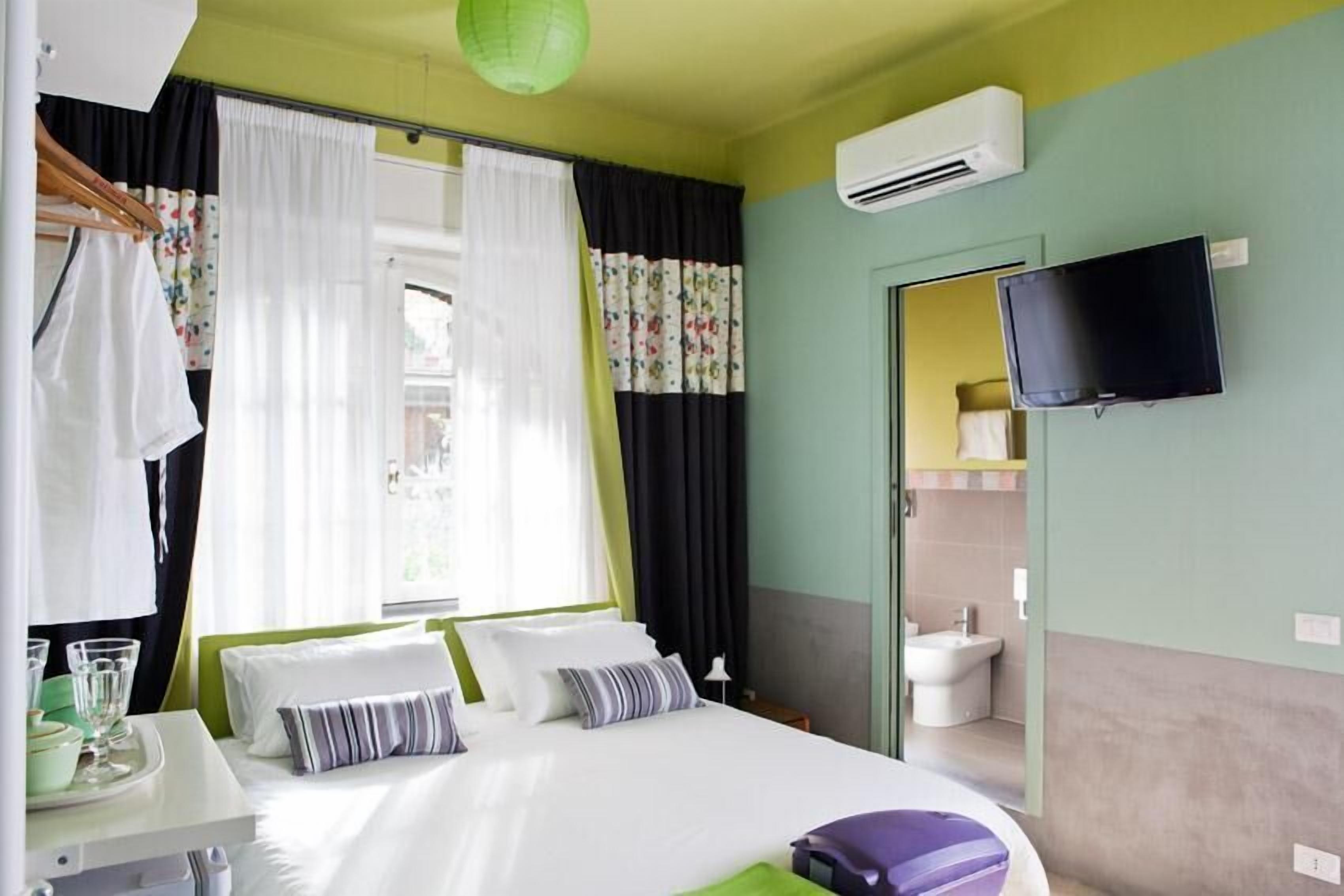 A hotel room with a bed, a TV, and a bathroom visible through an open door.