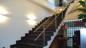 Una escalera moderna con barandilla de metal, que conduce a un rellano con partición de vidrio.