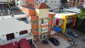A hotel with a prominent sign, multiple balconies, and a parking area with cars. - Hotel La Casa del Turista (Cartagena)