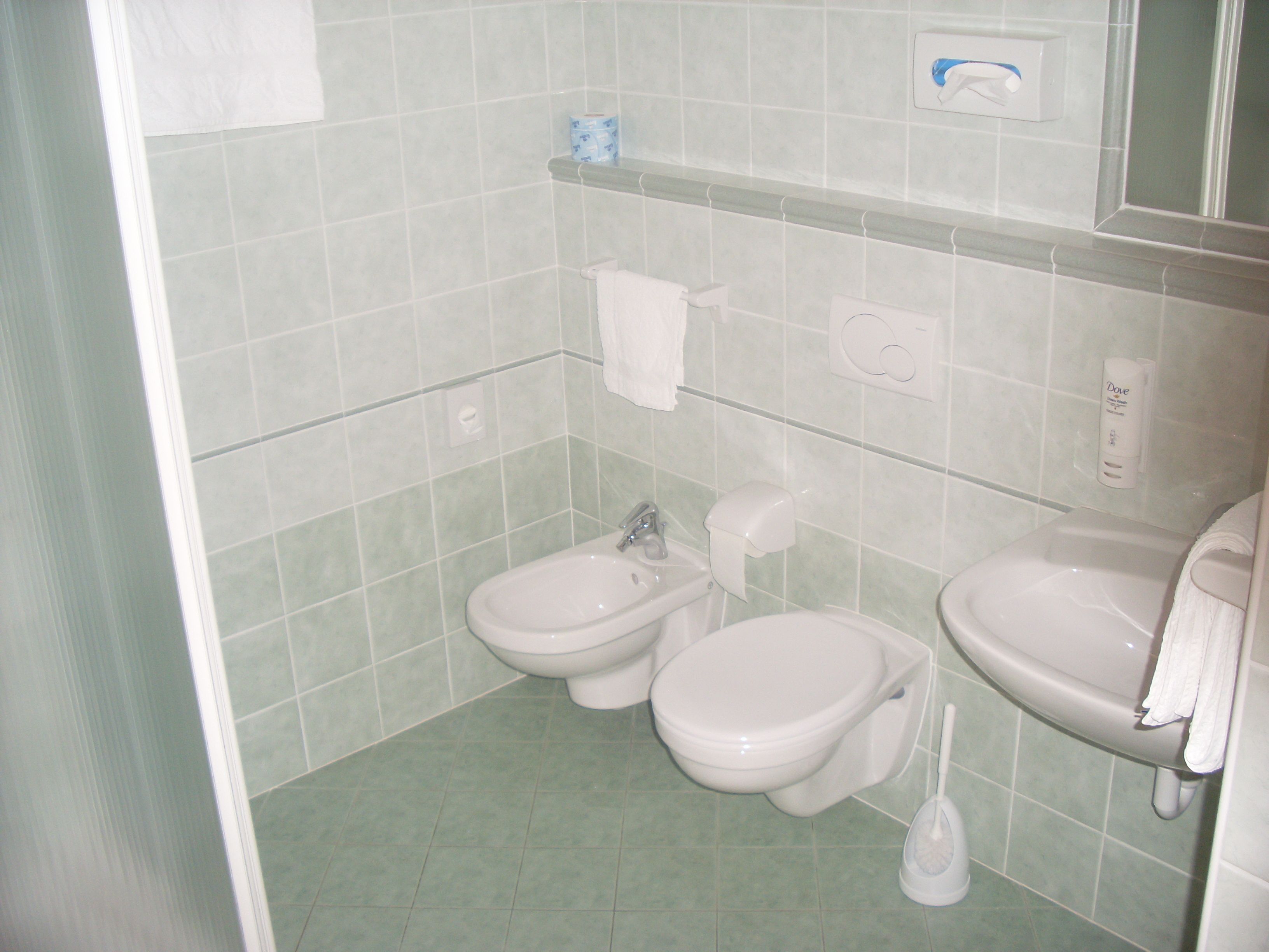 Ein Badezimmer mit Toilette, Bidet, Waschbecken und Handtrockner.