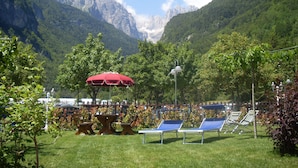 A mountain view with outdoor seating and a red umbrella. - Garnì Lago Alpino (Molveno)