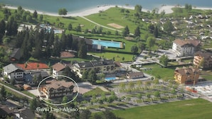 An aerial view of a residential area with a swimming pool, green spaces, and a beach. - Garnì Lago Alpino (Molveno)