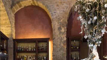 A bar area with stone arches, a Christmas tree, and shelves of liquor bottles.