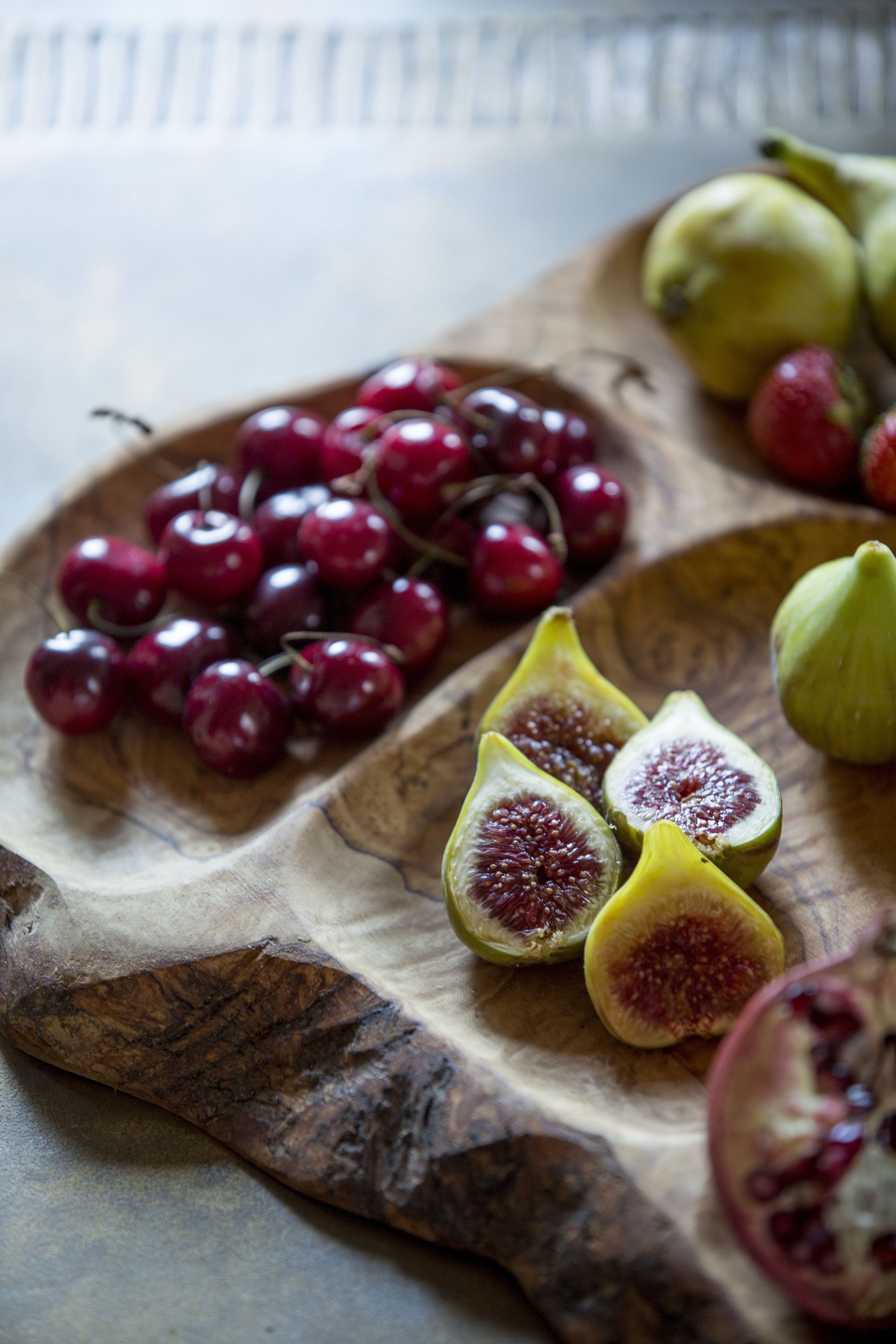 A wooden board with figs and cherries.