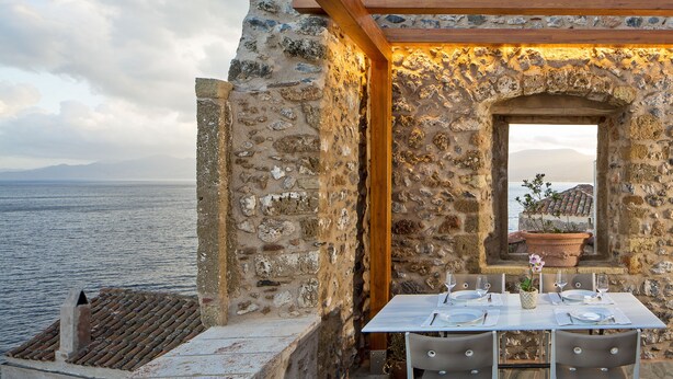 A stone building with a table set for two, overlooking the sea. - Moni Emvasis Luxury Suites (Monemvasia)