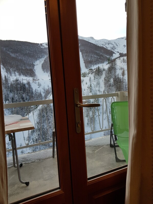 A room with a view of a snowy mountain landscape through a glass door.