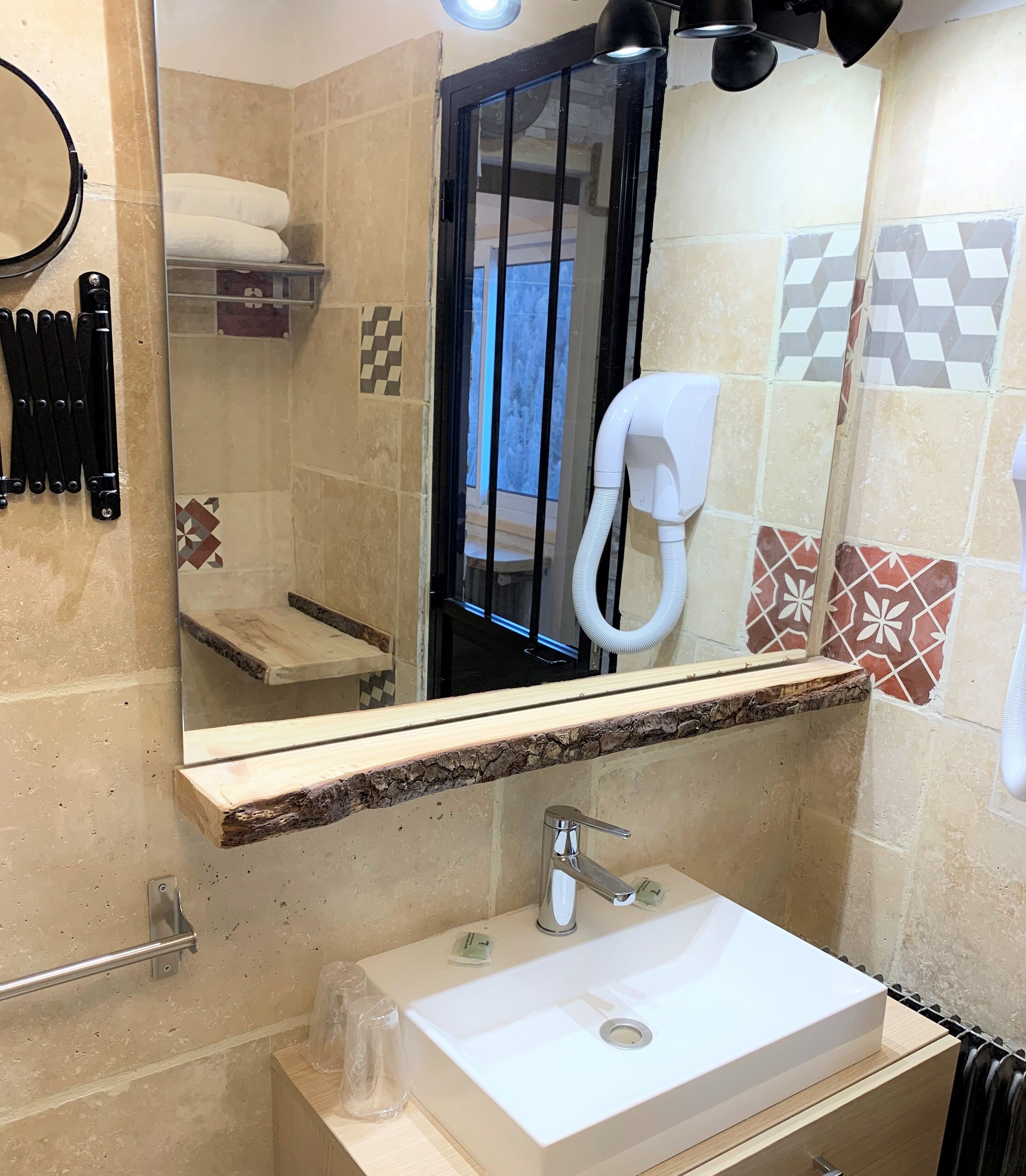 A bathroom with a sink, mirror, towel rack, and shower area.
