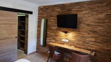 Una habitación con pared de madera, un televisor de pantalla plana sobre un escritorio y una silla.