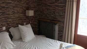 Et hotelværelse med en seng, hvide puder, et mønstret sengetæppe og en væg med træpaneldesign.
