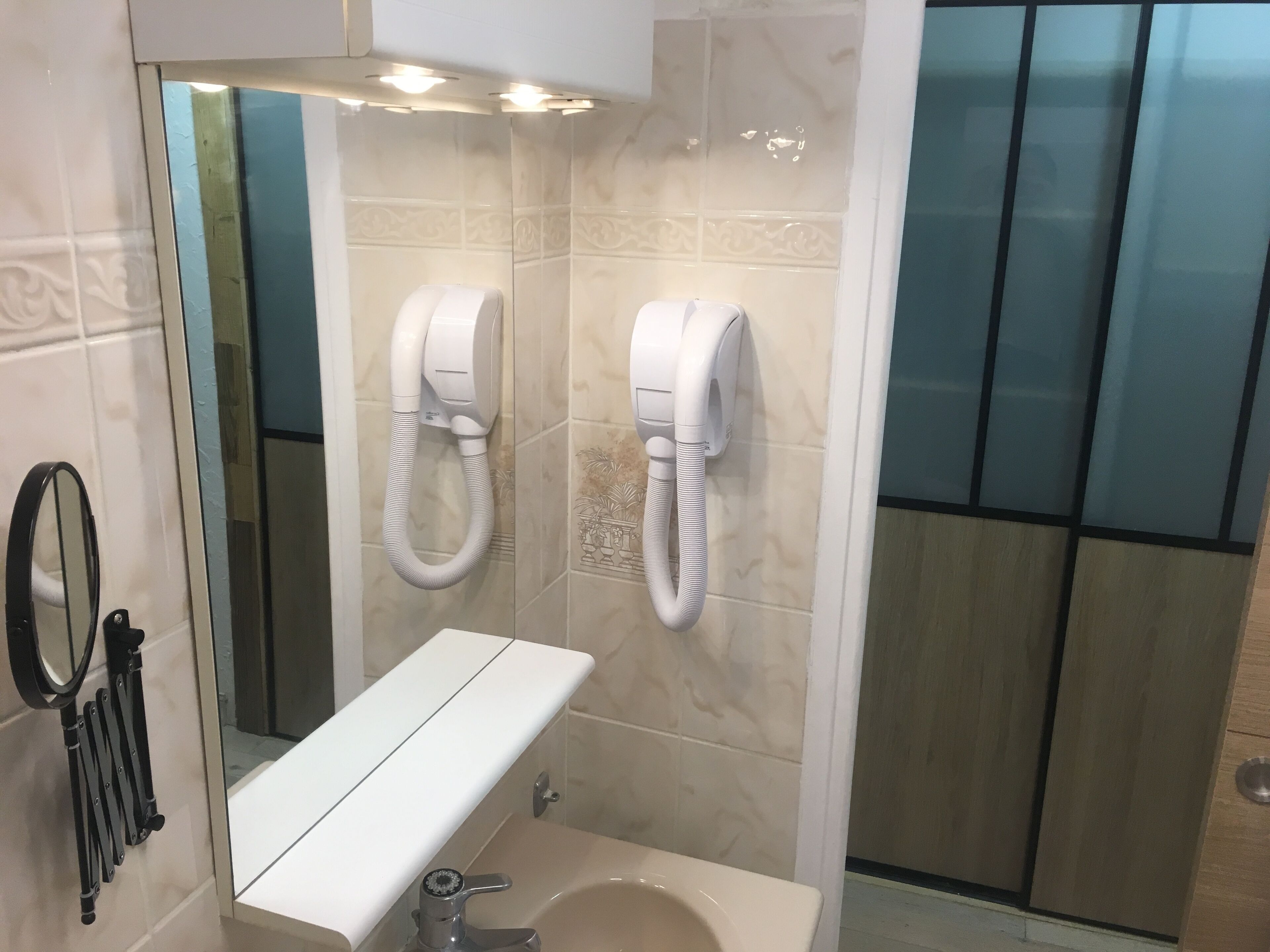 A bathroom with a sink, mirror, towel dispenser, and a toilet.
