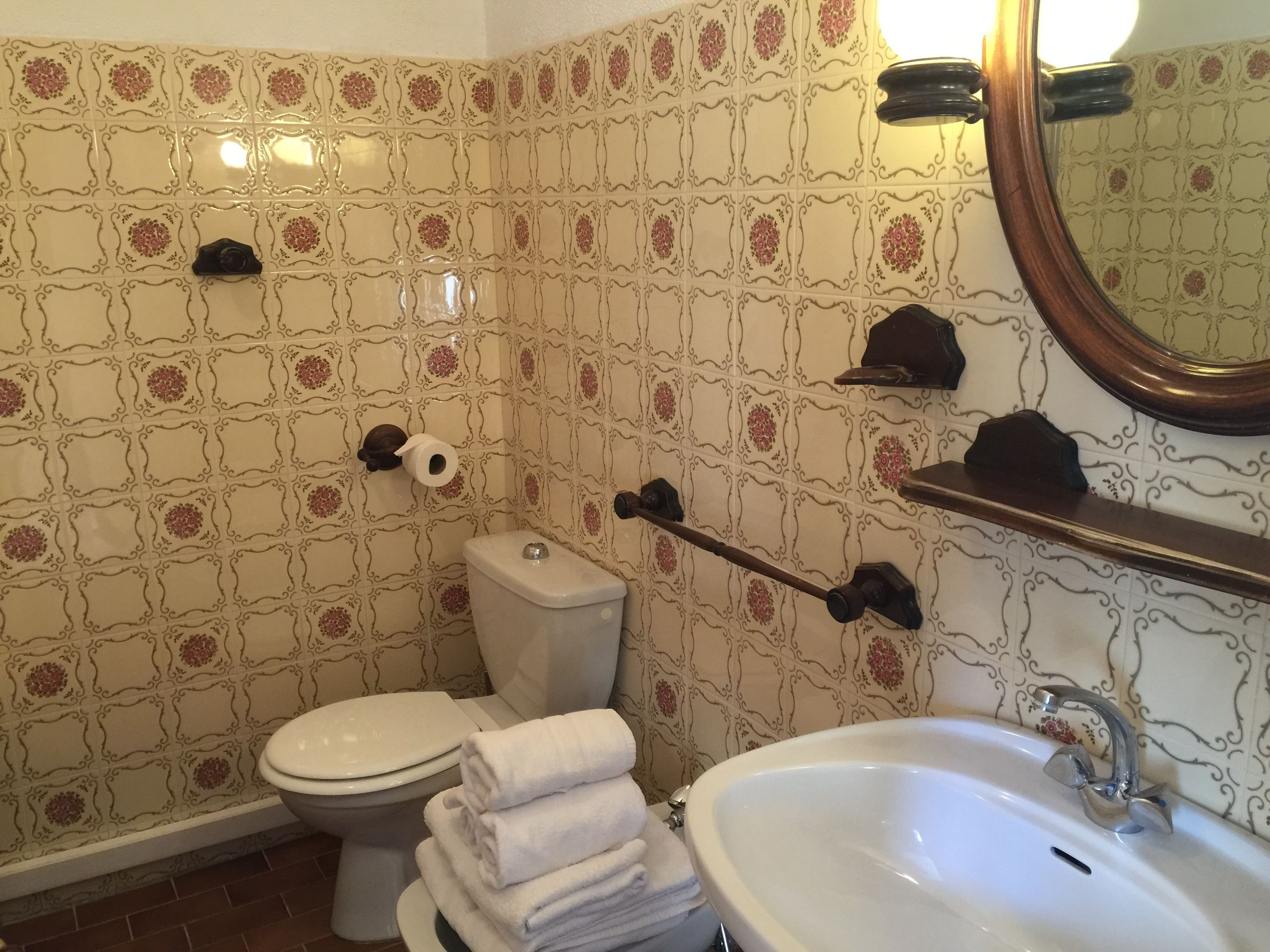 A bathroom with patterned tiles, a toilet, a sink, and a mirror.