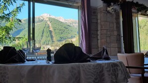 A table set for dining with a mountain view through large windows.