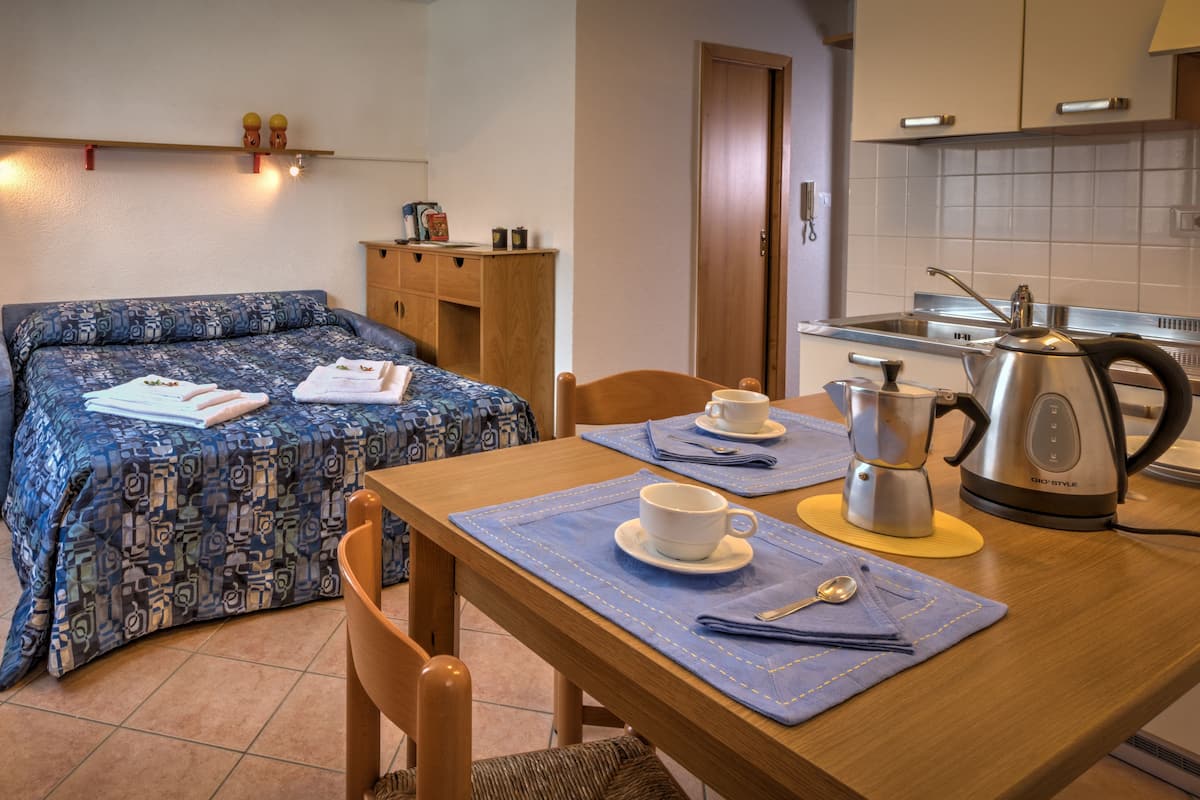Un dormitorio pequeño con cama, mesita de noche y una kitchenette.