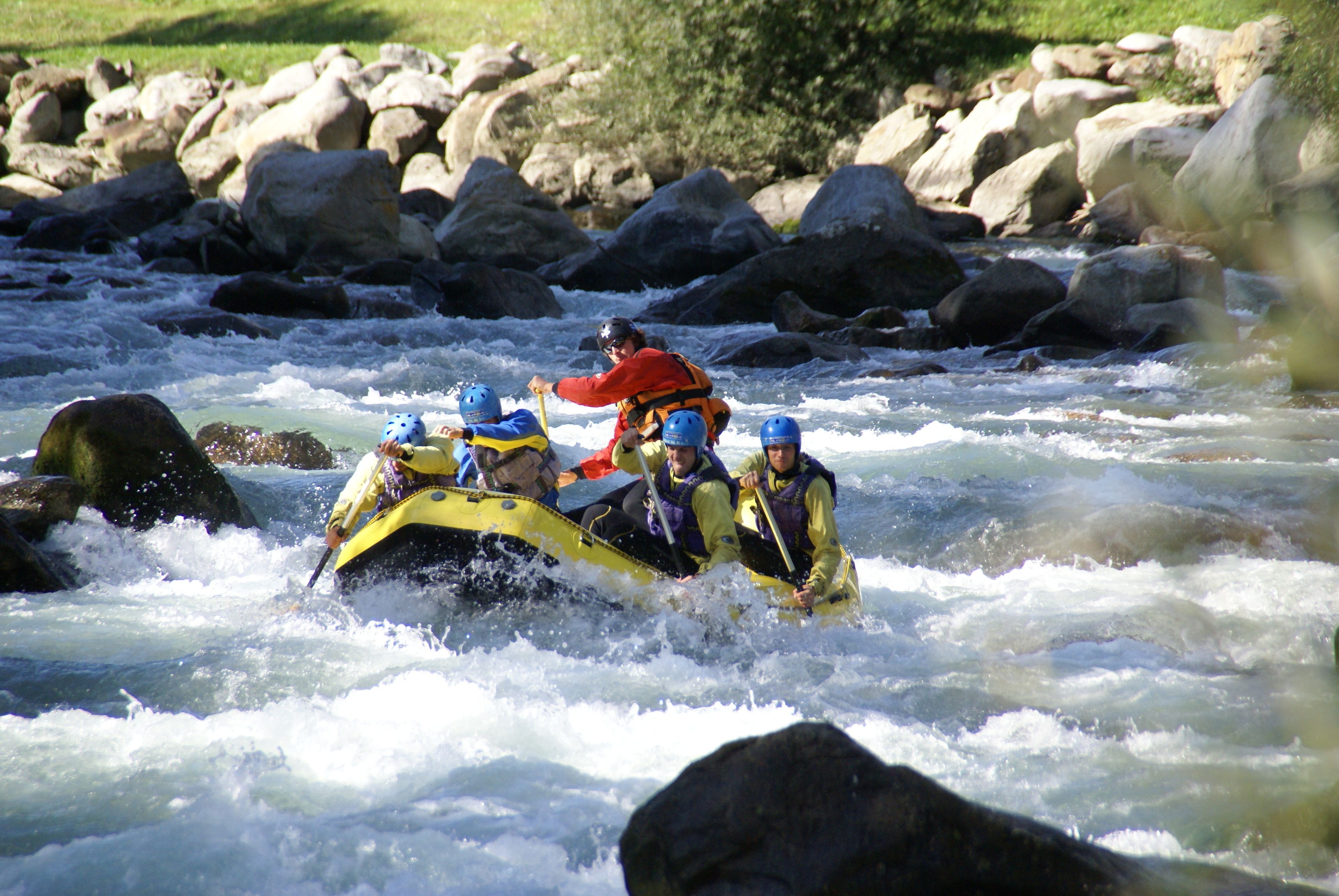 Un grupo de personas en un bote amarillo navegando un río con rocas.
