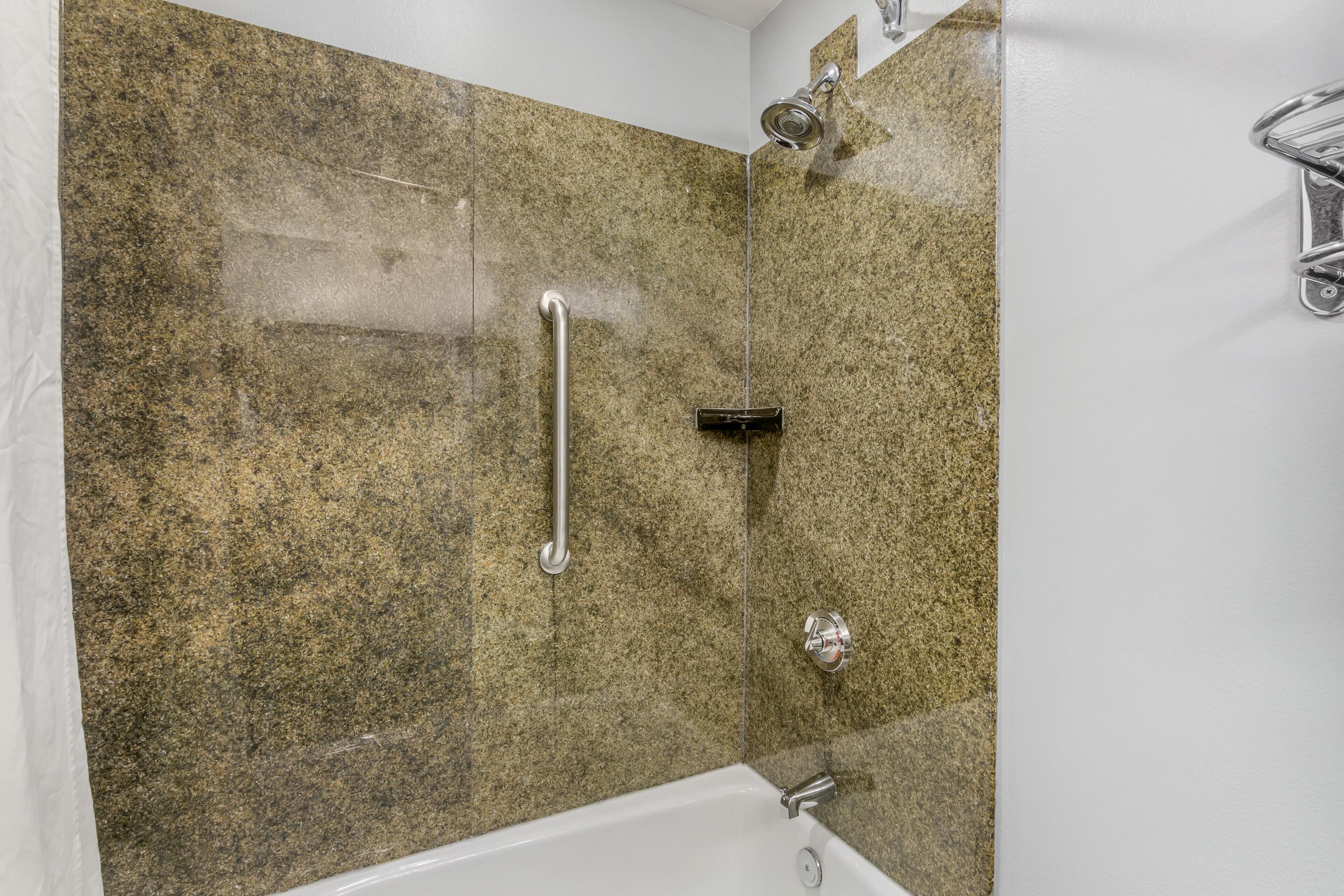 Une douche équipée d’un pommeau de douche à main, d’une barre de douche à main et d’un robinet mural.