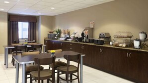 A modern kitchen with a dining area, equipped with a coffee maker, toaster, and food dispensers. - Microtel Inn & Suites Odessa TX (Odessa)