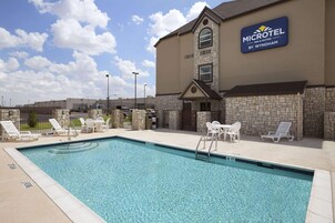 Una piscina con sillones de descanso y un cartel que dice 'MICROTEL INN & SUITES BY WYNDHAM'.