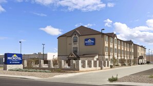 A Microtel by Wyndham hotel with a stone facade, multiple windows, and a parking lot. - Microtel Inn & Suites Odessa TX (Odessa)