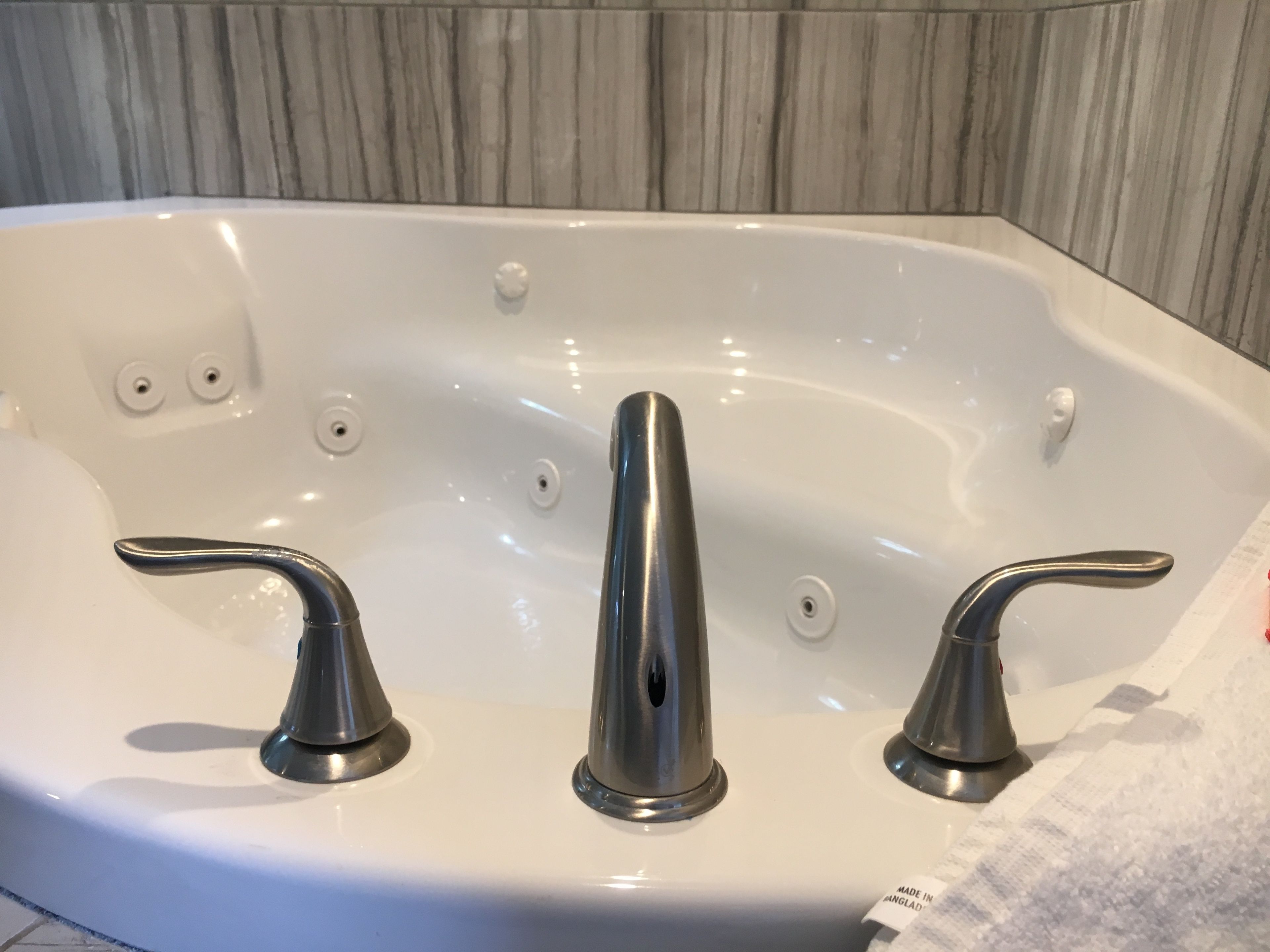 A white bathtub with three chrome faucets and a single control knob.