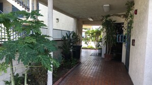 A covered walkway with tiled flooring, potted plants, and a staircase. - Bellflower Travel Inn (Bellflower)