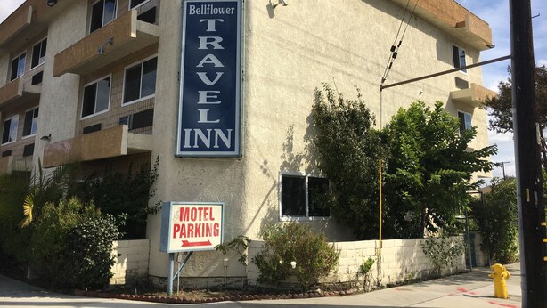 A building with a sign for Bellflower Travel Inn and a motel parking sign. - Bellflower Travel Inn (Bellflower)